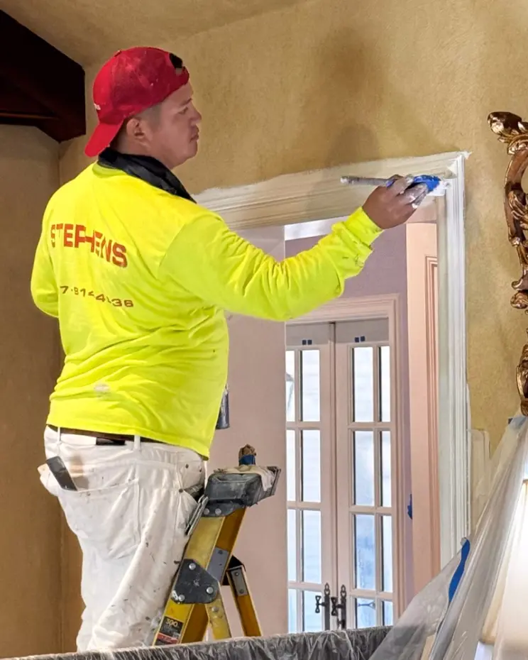 A Stephens Painting painter cutting in trim on a ladder